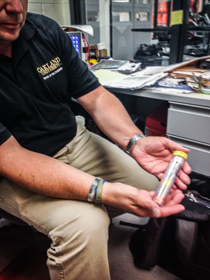 Thomas Ford, an OU athletic trainer, is given EpiPens from student athletes with allergies.