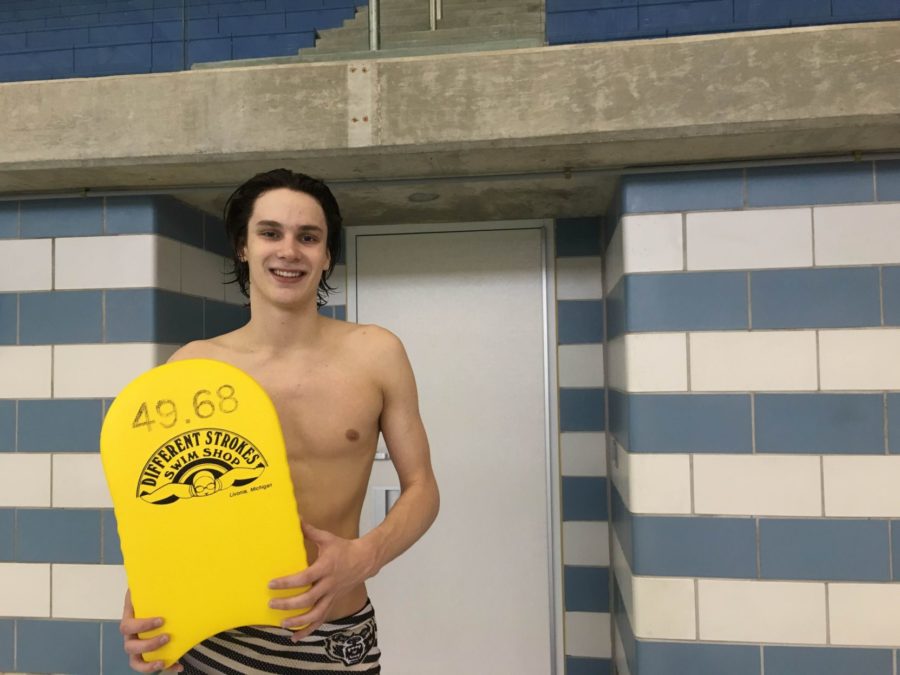 Freshman Devon Nowicki holds his kickboard, which is adorned with his goal for the 100 yard breaststroke.