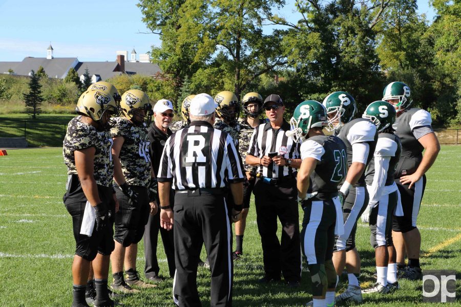 Oakland University President George Hynd joins in on the coin toss decision before the beginning of the game.