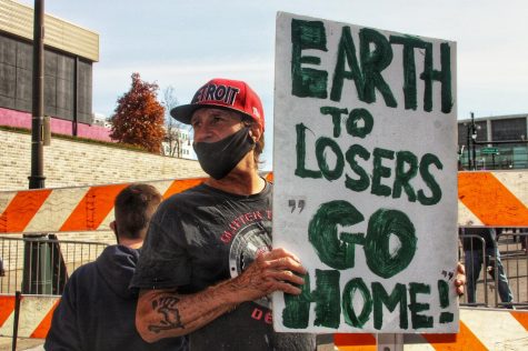 Counter protester Scott Koskinen, 55, of Detroit, carries a sign that said, “Earth to losers: Go home.” Photo by Rachel Basela.