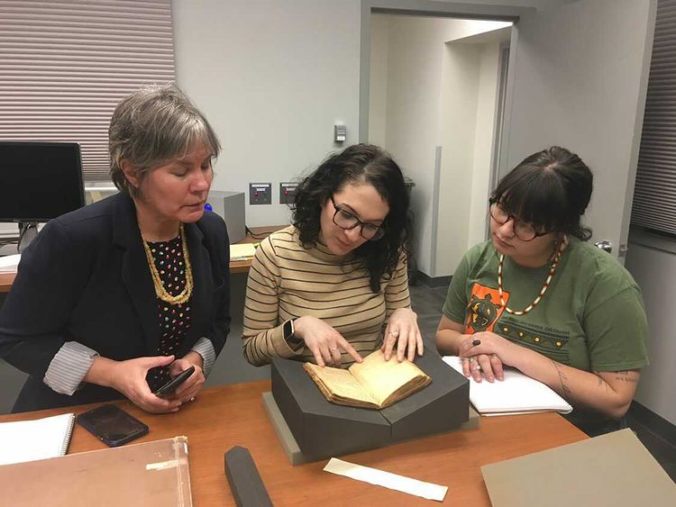 Left to right: Andrea Knutson, Megan Peiser and Ashleigh Dubie doing research while crafting OUs Land Acknowledgement Statement.